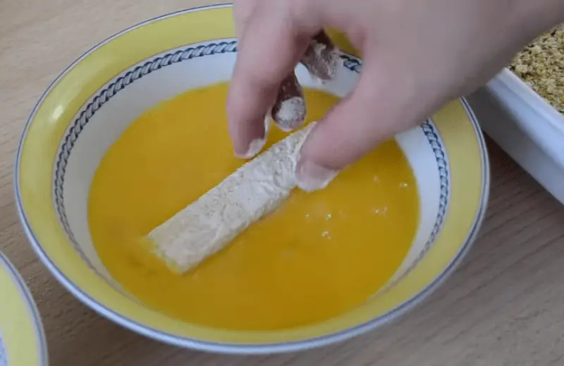 Pasar los palitos de queso por huevo