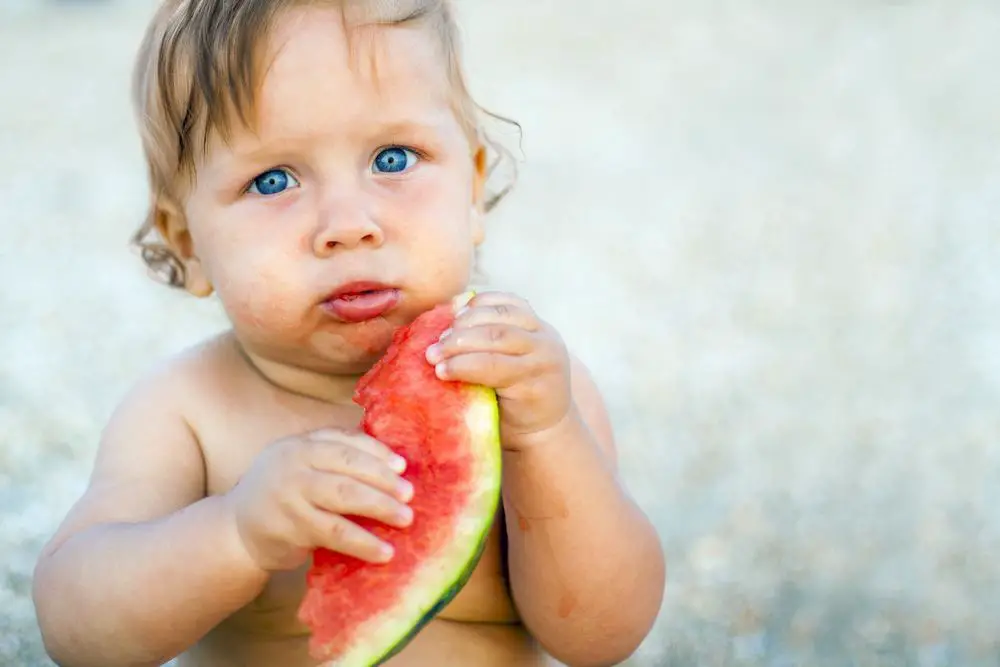 Bebé comiendo fruta fresca en verano